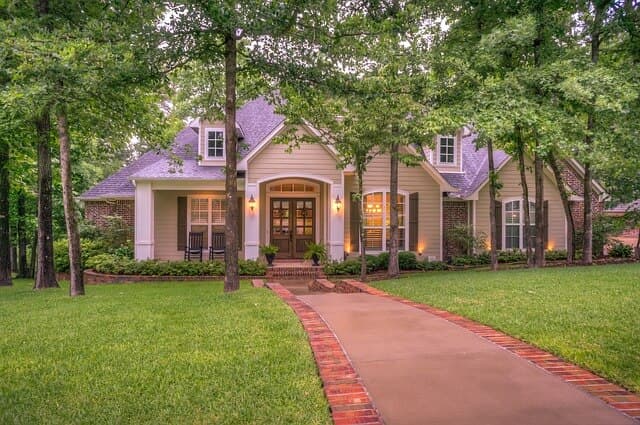Mature shade trees and a brick walkway in front of a home