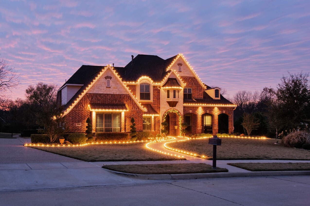 Home outlined with warm holiday lights at dusk